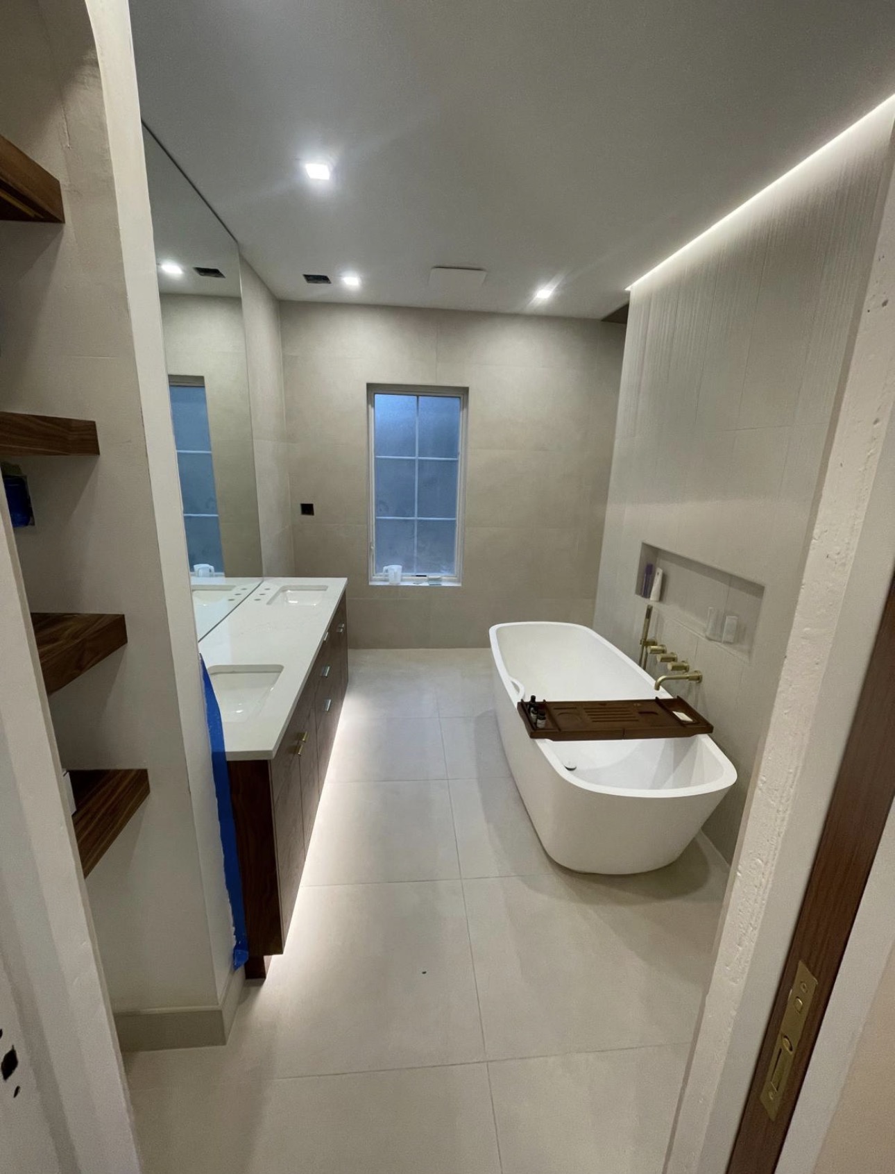 Finished master bathroom with freestanding tub, walnut vanity and large-format tile