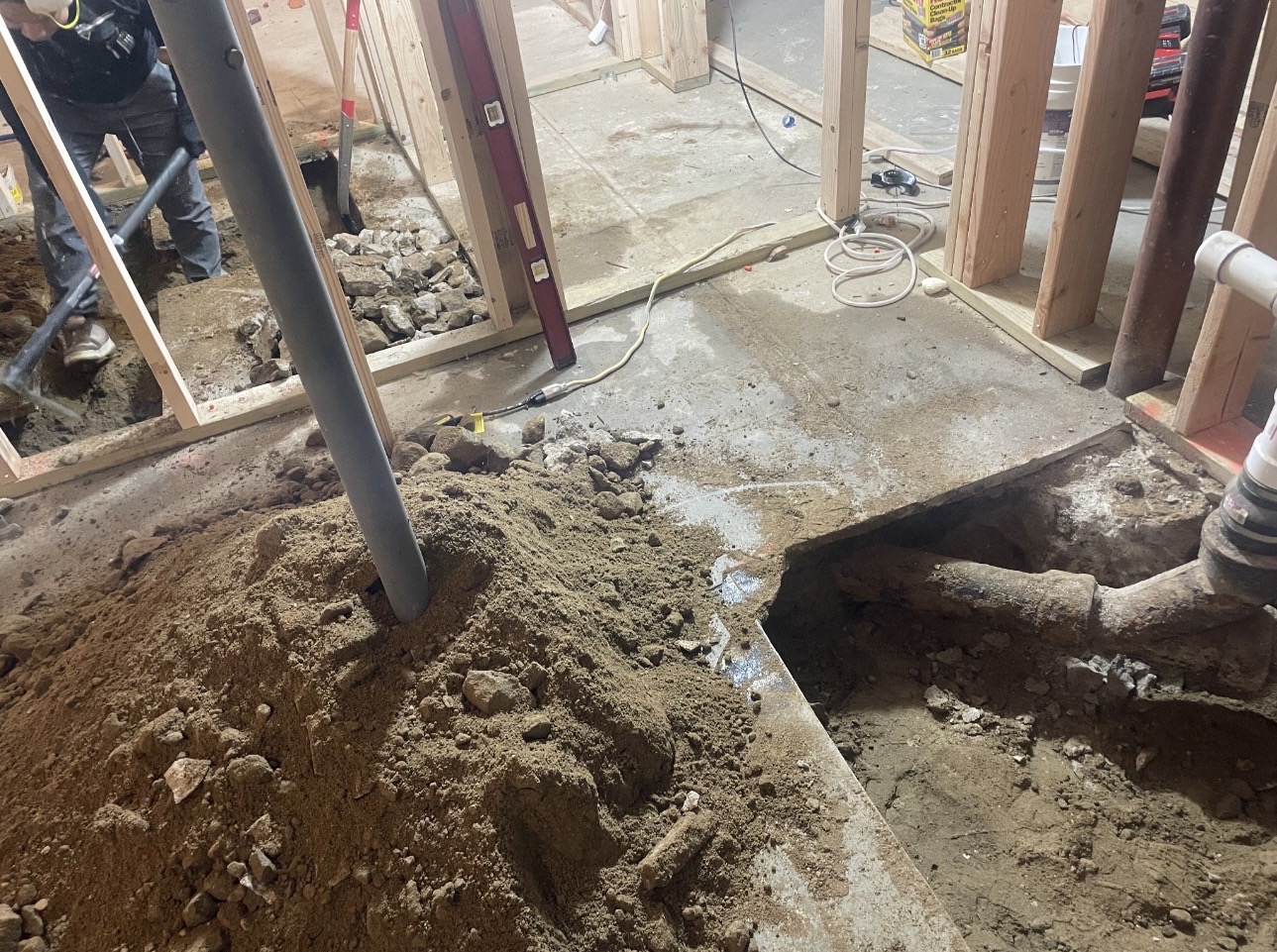 Basement renovation in progress: framed walls, concrete floor opened for drain lines