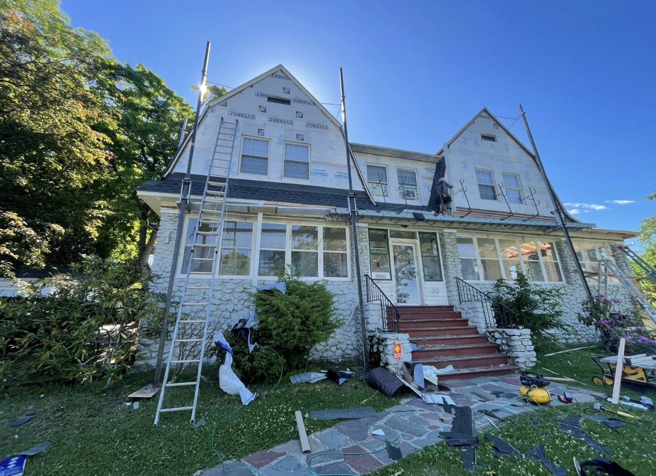 House mid re-side with foam sheathing on the gables, scaffolding, and ladders