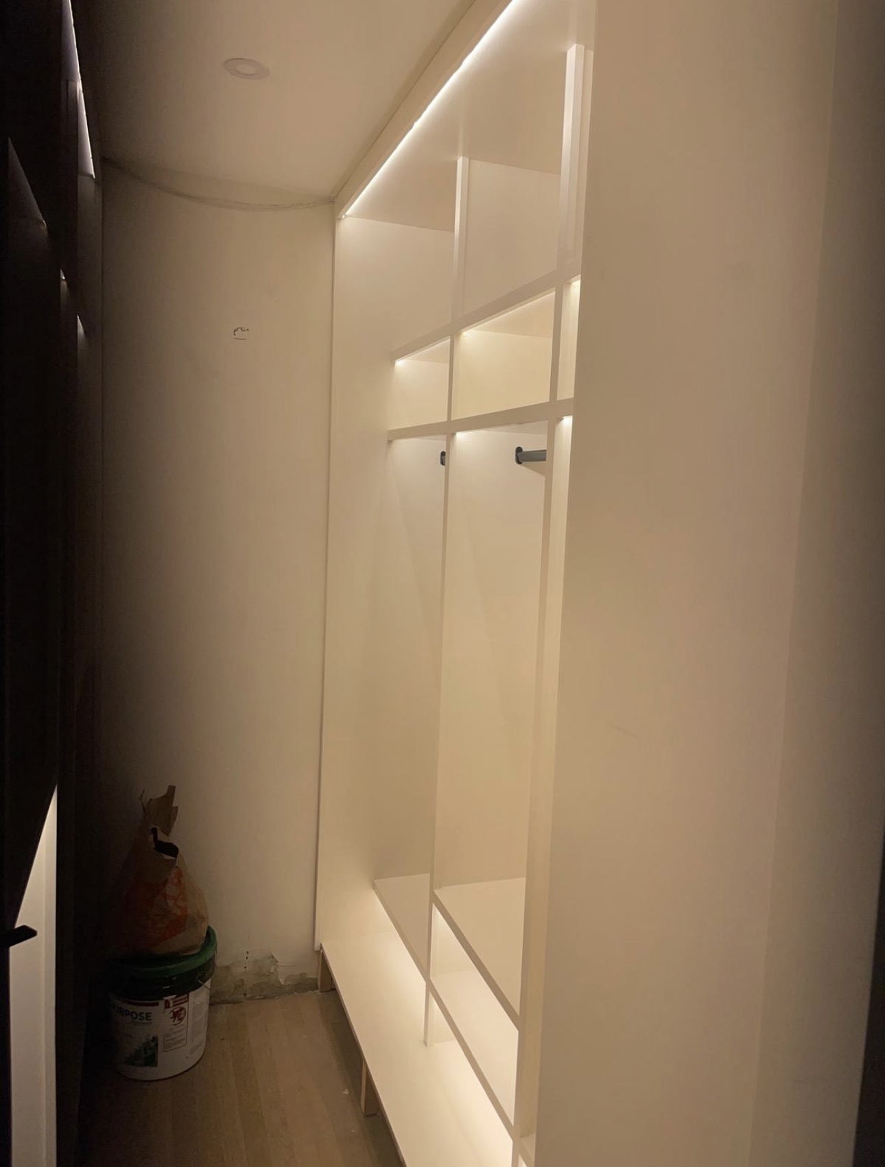 White built-in closet with LED-lit cubbies, hanging rod, and open millwork