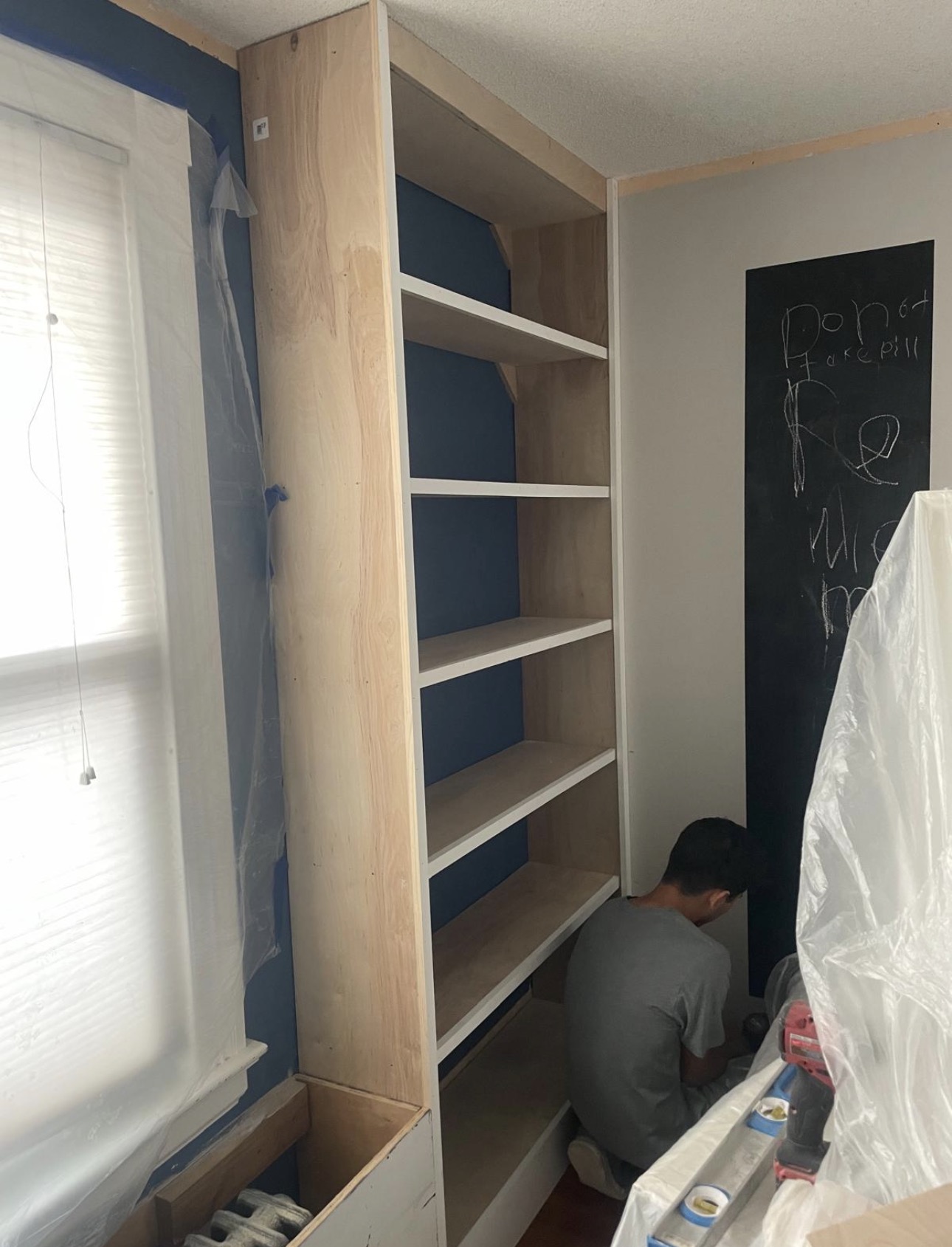 Built-in bookshelf being assembled in a blue room