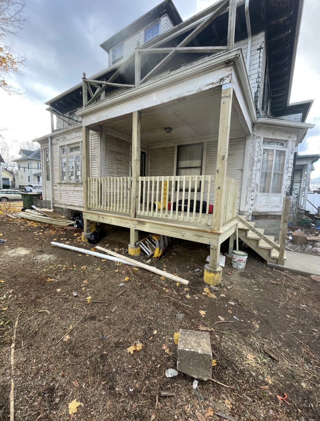 New wood porch framed onto a weathered Victorian house