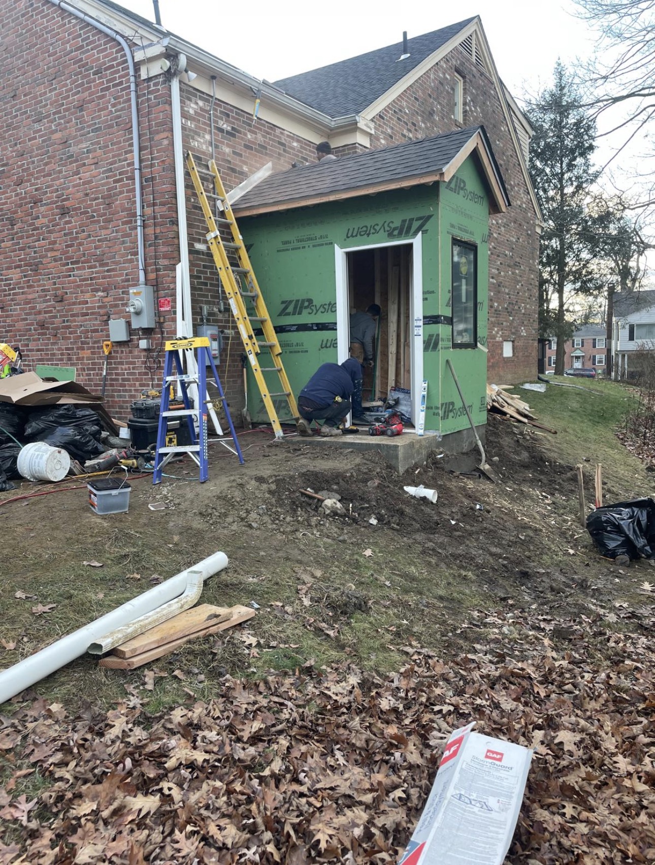 ZIP System–sheathed mudroom addition being framed onto a brick house