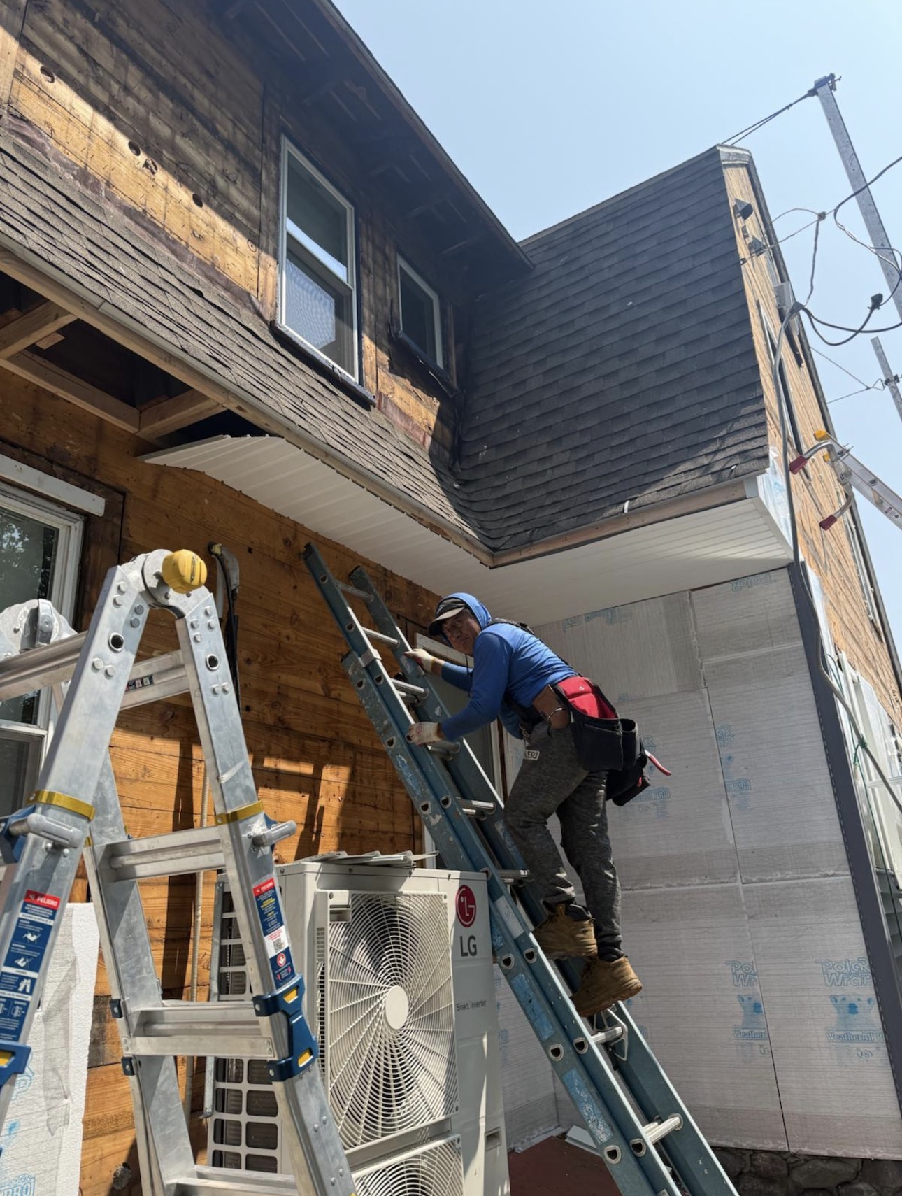 Carpenter on a ladder installing soffit and siding