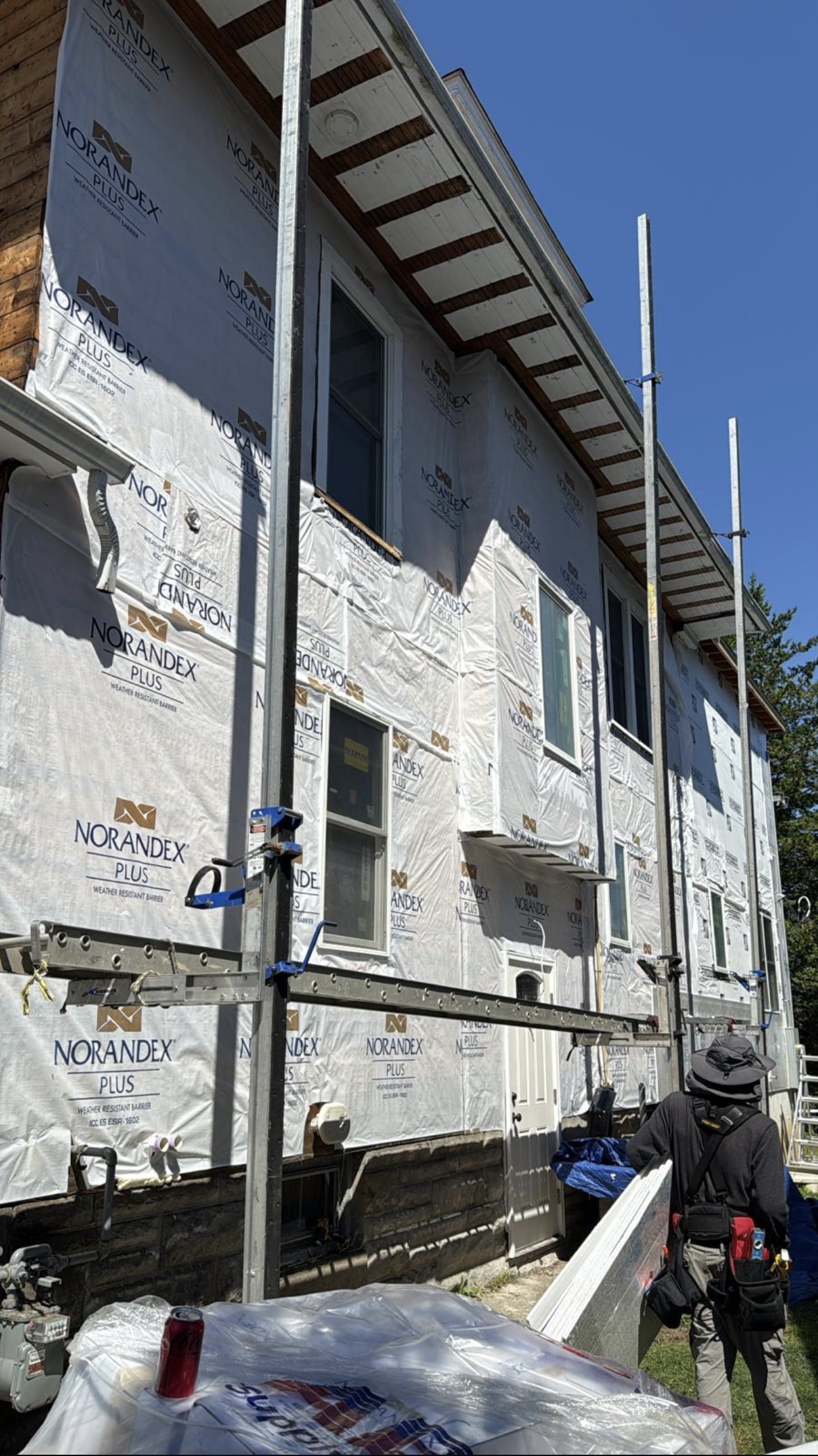 Elevation wrapped in Norandex housewrap, crew carrying white siding panels